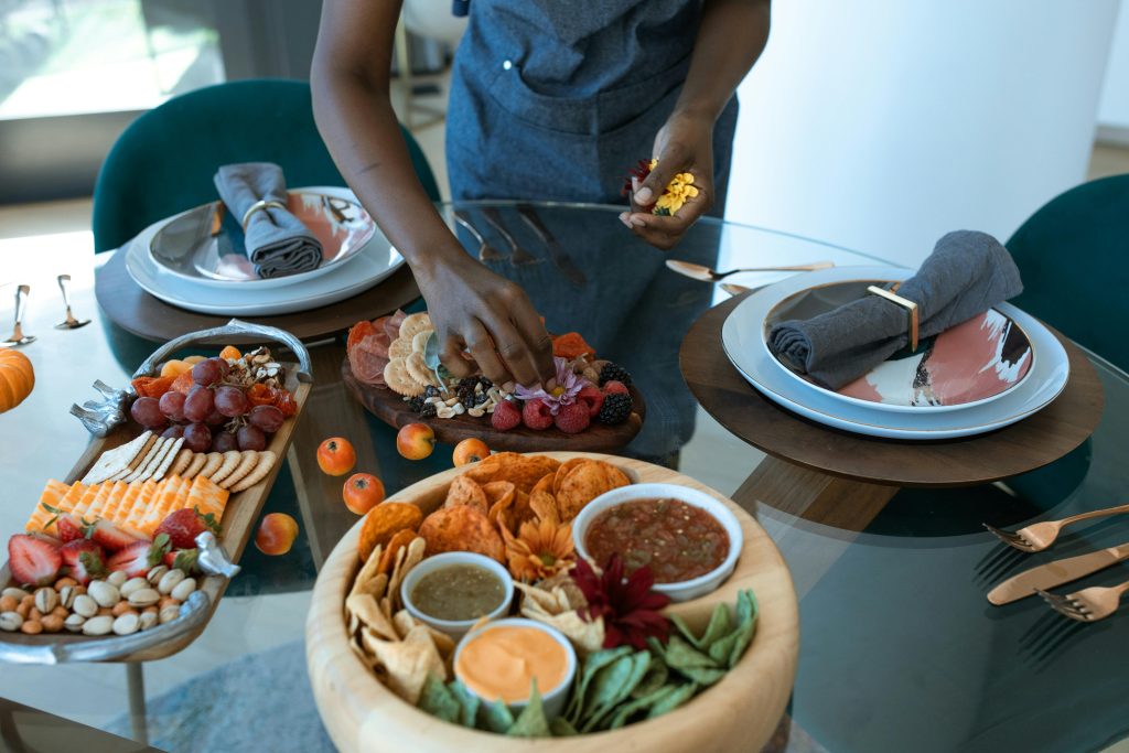 SERVICES A beautifully arranged grazing table with various fruits, cheeses, and dips on a glass table setting.